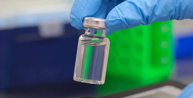 someone wearing blue gloves holding a small bottle